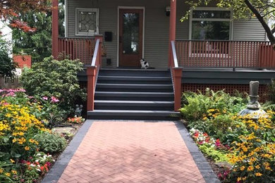 This is an example of a mid-sized traditional brick front porch design in Chicago with a roof extension.