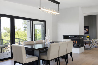Inspiration for a mid-sized contemporary light wood floor kitchen/dining room combo remodel in Salt Lake City with white walls and a two-sided fireplace