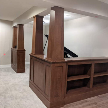 Basement with a banquette, beams, wainscot and bookcases