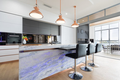 Inspiration for a contemporary kitchen in Gold Coast - Tweed with marble benchtops, metallic splashback, light hardwood floors, a peninsula and beige floor.