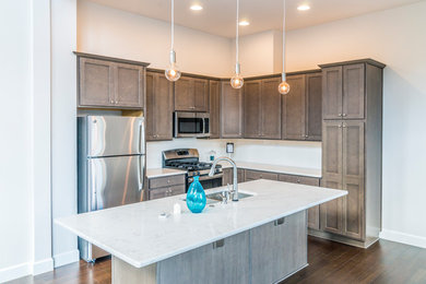 Inspiration for a mid-sized transitional l-shaped medium tone wood floor and brown floor open concept kitchen remodel in Portland with a double-bowl sink, shaker cabinets, medium tone wood cabinets, quartzite countertops, stainless steel appliances and an island