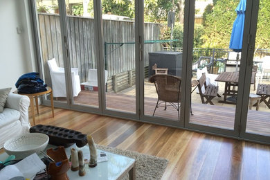 This is an example of a mid-sized contemporary backyard verandah in Sydney with an outdoor kitchen, brick pavers and a roof extension.