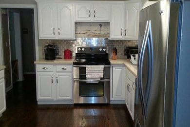 Enclosed kitchen - mid-sized contemporary l-shaped dark wood floor enclosed kitchen idea in New York with raised-panel cabinets, white cabinets, solid surface countertops, metallic backsplash, metal backsplash, stainless steel appliances and no island