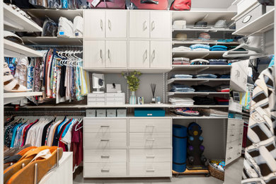 Example of a mid-sized minimalist women's concrete floor and gray floor walk-in closet design in Austin with flat-panel cabinets and light wood cabinets