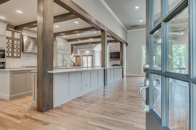 This is an example of an expansive single-wall kitchen in Oklahoma City with shaker cabinets, grey cabinets, quartz benchtops, marble splashback, stainless steel appliances, light hardwood floors, multiple islands and white benchtop.