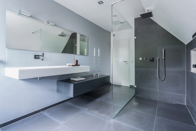 Mittelgroßes Modernes Duschbad mit flächenbündigen Schrankfronten, grauen Schränken, bodengleicher Dusche, Wandtoilette, grauen Fliesen, weißer Wandfarbe, Aufsatzwaschbecken, grauem Boden, offener Dusche und weißer Waschtischplatte in Stuttgart