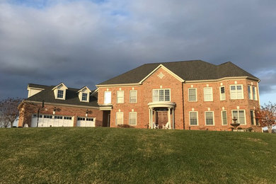 Large elegant brick house exterior photo in Richmond with a hip roof and a shingle roof