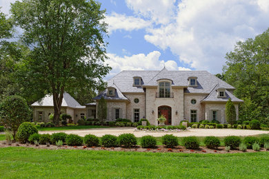 Large traditional beige three-story brick exterior home idea in DC Metro with a hip roof