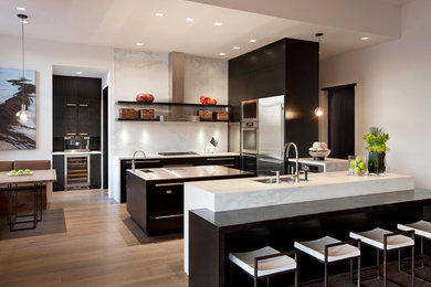 Inspiration for a mediterranean u-shaped medium tone wood floor eat-in kitchen remodel in Santa Barbara with a double-bowl sink, flat-panel cabinets, dark wood cabinets, white backsplash, stainless steel appliances and an island