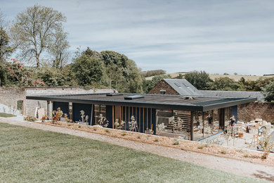 Photo of a medium sized contemporary bungalow detached house in Devon with a flat roof and a green roof.