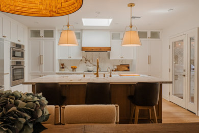 Eat-in kitchen - mid-sized contemporary medium tone wood floor and beige floor eat-in kitchen idea in Los Angeles with a single-bowl sink, shaker cabinets, medium tone wood cabinets, solid surface countertops, white backsplash, stone slab backsplash, stainless steel appliances, an island and white countertops