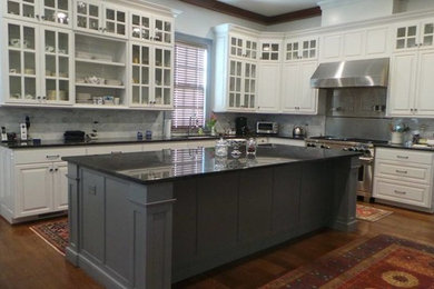 Inspiration for a huge timeless l-shaped medium tone wood floor eat-in kitchen remodel in Other with an undermount sink, raised-panel cabinets, white cabinets, granite countertops, multicolored backsplash, stone tile backsplash, stainless steel appliances and an island