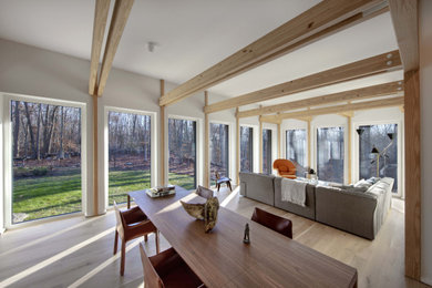 Imagen de sala de estar abierta y blanca moderna de tamaño medio con paredes blancas, suelo de madera clara y vigas vistas