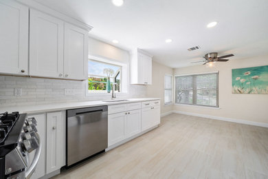Eat-in kitchen - mid-sized farmhouse u-shaped porcelain tile and white floor eat-in kitchen idea in Austin with an undermount sink, shaker cabinets, white cabinets, quartz countertops, white backsplash, porcelain backsplash, stainless steel appliances, no island and white countertops