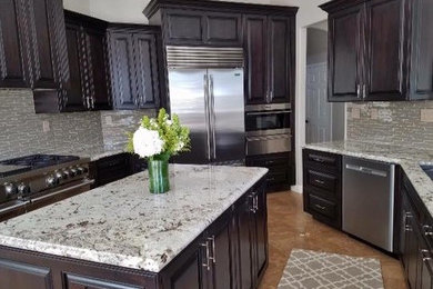 Inspiration for a large timeless u-shaped travertine floor and beige floor enclosed kitchen remodel in Other with a double-bowl sink, raised-panel cabinets, dark wood cabinets, granite countertops, stainless steel appliances and an island