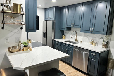 Inspiration for a transitional galley ceramic tile and brown floor kitchen remodel in Los Angeles with an undermount sink, raised-panel cabinets, blue cabinets, quartz countertops, white backsplash, quartz backsplash, stainless steel appliances and white countertops
