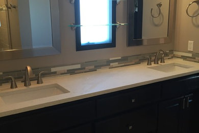 Photo of a mid-sized transitional master wet room bathroom in Omaha with raised-panel cabinets, black cabinets, a two-piece toilet, gray tile, mosaic tile, grey walls, ceramic floors, an undermount sink, quartzite benchtops, grey floor, a hinged shower door and white benchtops.