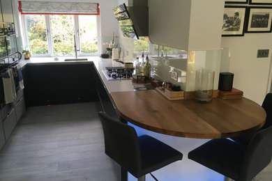 Photo of a mid-sized modern u-shaped eat-in kitchen in Hampshire with a drop-in sink, flat-panel cabinets, grey cabinets, quartzite benchtops, white splashback, glass sheet splashback, stainless steel appliances, vinyl floors, no island, grey floor and white benchtop.