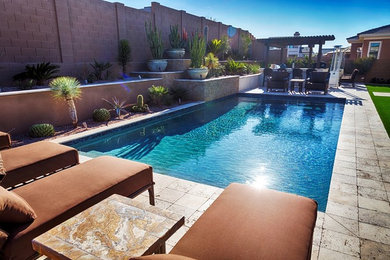 This is an example of a large traditional backyard pool in Phoenix with a water feature and stamped concrete.