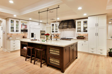 Design ideas for a large transitional l-shaped open plan kitchen in Phoenix with a farmhouse sink, shaker cabinets, white cabinets, granite benchtops, white splashback, subway tile splashback, stainless steel appliances, light hardwood floors, with island, brown floor and beige benchtop.