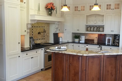 Inspiration for a mid-sized timeless l-shaped kitchen remodel in Denver with recessed-panel cabinets, white cabinets, granite countertops, beige backsplash, stone tile backsplash, stainless steel appliances, an island and a farmhouse sink