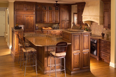 Huge elegant medium tone wood floor kitchen photo in Wichita with an undermount sink, raised-panel cabinets, medium tone wood cabinets, granite countertops, stone slab backsplash, paneled appliances, an island and beige backsplash