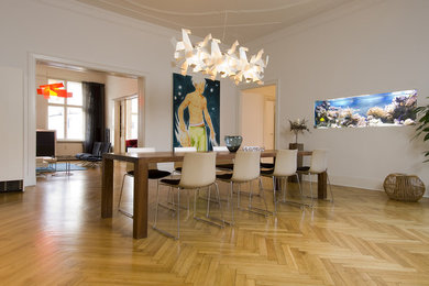 Contemporary open plan dining in Berlin with white walls and light hardwood floors.