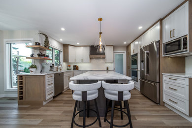 Example of an u-shaped beige floor kitchen design in Edmonton with white cabinets, subway tile backsplash, stainless steel appliances, an island and white countertops