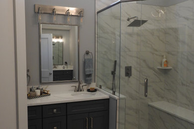 Inspiration for a large transitional master gray tile and stone tile single-sink and vaulted ceiling bathroom remodel in Atlanta with shaker cabinets, black cabinets, gray walls, an undermount sink, quartz countertops, a hinged shower door, white countertops and a built-in vanity
