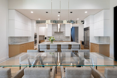Example of a mid-sized minimalist u-shaped light wood floor open concept kitchen design in Dallas with an undermount sink, flat-panel cabinets, white cabinets, quartzite countertops, white backsplash, paneled appliances, an island and white countertops