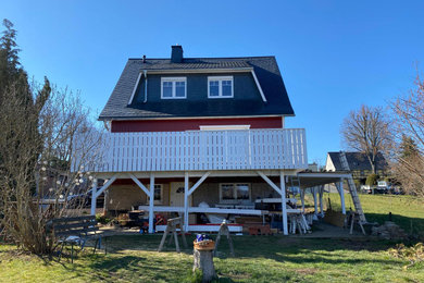 Ejemplo de fachada de casa bifamiliar roja y gris nórdica de tamaño medio de dos plantas con revestimiento de madera, tejado a dos aguas y tejado de teja de madera