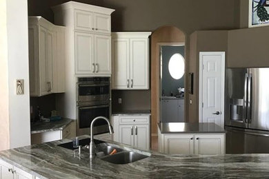 Inspiration for a timeless galley eat-in kitchen remodel in Tampa with an undermount sink, recessed-panel cabinets, beige cabinets, granite countertops, stainless steel appliances and an island