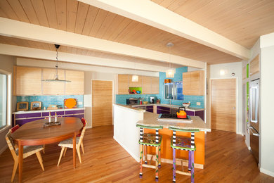 This is an example of a mid-sized eclectic u-shaped eat-in kitchen in San Luis Obispo with flat-panel cabinets, light wood cabinets, subway tile splashback, stainless steel appliances, an undermount sink, blue splashback, medium hardwood floors, a peninsula, brown floor, recycled glass benchtops and multi-coloured benchtop.