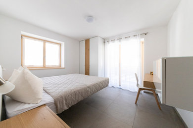 Foto di una camera matrimoniale minimalista di medie dimensioni con pareti bianche, pavimento in gres porcellanato e pavimento grigio