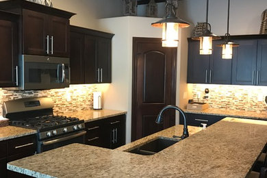 Transitional l-shaped kitchen photo in Other with an undermount sink, flat-panel cabinets, dark wood cabinets, granite countertops, multicolored backsplash, ceramic backsplash, stainless steel appliances and an island
