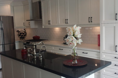 Inspiration for a mid-sized contemporary l-shaped slate floor eat-in kitchen remodel in Toronto with a farmhouse sink, shaker cabinets, white cabinets, marble countertops, white backsplash, subway tile backsplash, stainless steel appliances and an island