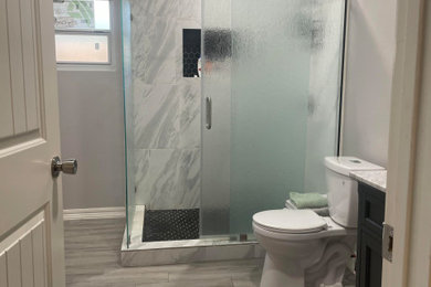 Sliding shower door - contemporary medium tone wood floor and gray floor sliding shower door idea in Houston with a two-piece toilet and yellow walls