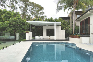 This is an example of a small contemporary backyard custom-shaped pool in Sydney with a pool house and tile.