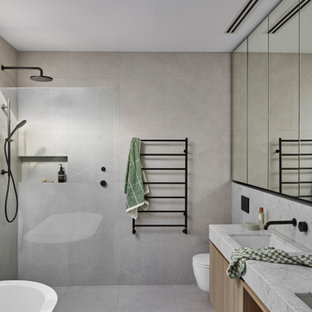Photo of a mid-sized contemporary master bathroom in Melbourne with marble benchtops, grey floor, white benchtops, a built-in vanity, a freestanding tub, a curbless shower, a wall-mount toilet, gray tile, stone tile, grey walls, an undermount sink, an open shower and a double vanity.