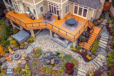 This is an example of a large arts and crafts backyard deck in Seattle with a fire feature and no cover.