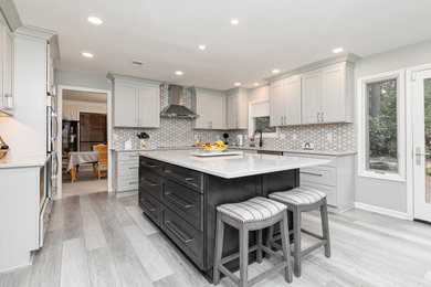Large minimalist laminate floor kitchen photo in Atlanta with an undermount sink, shaker cabinets, gray cabinets, quartz countertops, porcelain backsplash, stainless steel appliances, an island and white countertops