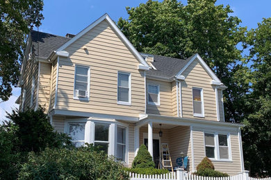 Modelo de fachada de casa beige clásica de dos plantas con revestimiento de vinilo