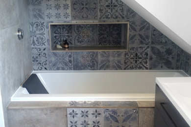 This is an example of a large modern ensuite bathroom with grey cabinets, a built-in bath, a walk-in shower, multi-coloured tiles, ceramic tiles, white walls, ceramic flooring and a wall-mounted sink.
