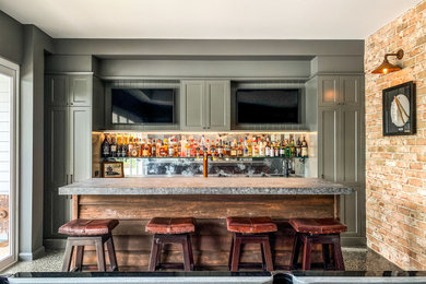 This is an example of a transitional galley seated home bar in Sunshine Coast with shaker cabinets, green cabinets, mirror splashback and grey benchtop.