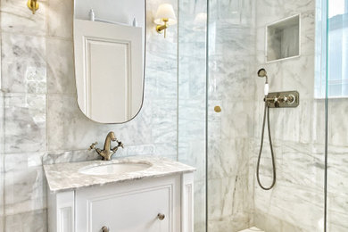 Photo of a victorian grey and white shower room bathroom in London with beaded cabinets, white cabinets, a corner shower, a wall mounted toilet, white tiles, marble tiles, white walls, ceramic flooring, a built-in sink, marble worktops, multi-coloured floors, a hinged door, white worktops, feature lighting, a single sink and a freestanding vanity unit.