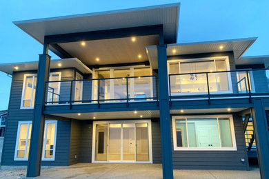 Example of a large minimalist two-story concrete fiberboard house exterior design in Other