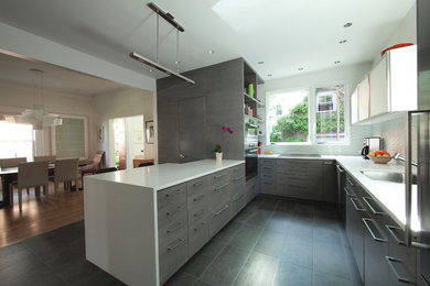 Minimalist u-shaped eat-in kitchen photo in New York with an undermount sink, flat-panel cabinets, gray cabinets, solid surface countertops, glass tile backsplash and stainless steel appliances