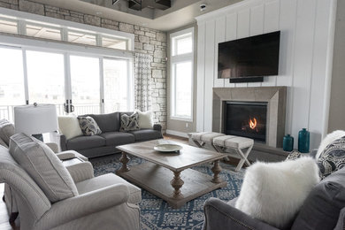 Inspiration for a large beach style enclosed family room in Denver with grey walls, a wall-mounted tv, dark hardwood floors, a standard fireplace, a concrete fireplace surround and brown floor.