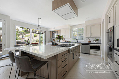 Example of a large arts and crafts l-shaped porcelain tile, beige floor and vaulted ceiling eat-in kitchen design in San Diego with an undermount sink, shaker cabinets, white cabinets, quartzite countertops, white backsplash, stone tile backsplash, stainless steel appliances, an island and white countertops