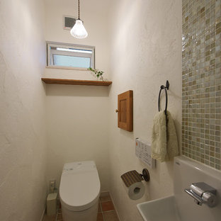 他の地域のカントリー風おしゃれなトイレ・洗面所 (一体型トイレ 、白い壁、磁器タイルの床、マルチカラーの床) の写真